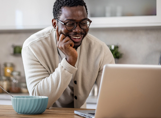 A smiling man using his laptop at home
