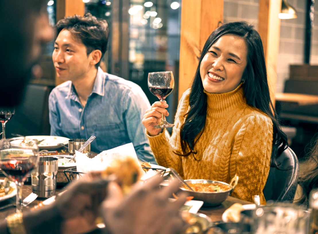 A laughing couple dines with friends at a nearby restaurant